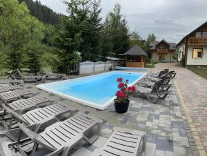 a pool with lounge chairs and a gazebo at Ilkova Sadyba in Yaremche