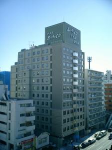 wysoki budynek z znakiem na górze w obiekcie Hotel Route-Inn Nagoya Higashi Betsuin w mieście Nagoja