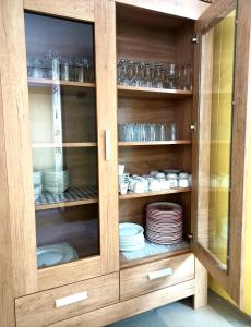 a wooden cabinet with plates and dishes in it at Pensiunea Roșu Litoral in Douăzeci şi Trei August