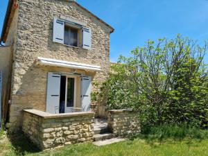 Casa de piedra con puerta blanca y ventana en Charmant petit havre de paix en Dauphin