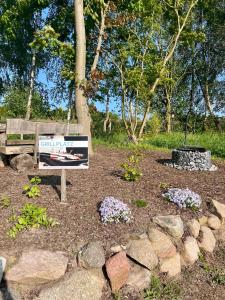 a park with a bench and flowers and a sign at Naturidyll Mariendorf - Reethus Rotbuche in Mariendorf