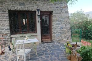 a stone house with a table and a chair in front of a door at appartement en rez de jardin CYCLISTES BIEN VENUS in Prades
