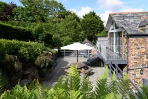 an outdoor patio with an umbrella and benches at Tranquil Cornish retreat close to Port Isaac beaches and moor in Bodmin