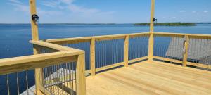 a wooden deck with a view of the water at Loza house adirondack skydeck unit lake front in Plattsburgh