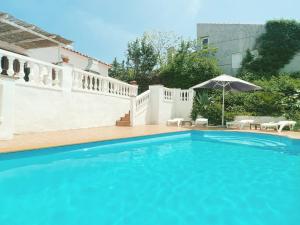 - une piscine avec un parasol en face d'une maison dans l'établissement Villa Mas Blau Munt, à Lloret de Mar