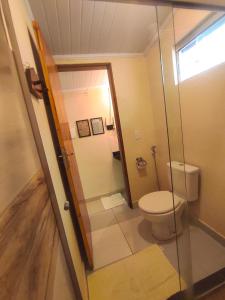 a bathroom with a toilet and a glass door at Chalé com ar condicionado e garagem in Alto Paraíso de Goiás