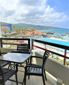 a balcony with chairs and a table and a pool at Chalet at Aqualand Resort in Batroûn