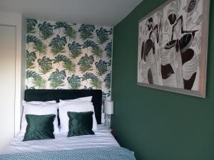 a bedroom with a bed with green walls and a painting at Le Cocon Vert in Rueil-Malmaison