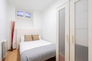a white bedroom with a white bed and a window at Cosy interior ground floor in Barrio Salamanca-BOC5 in Madrid