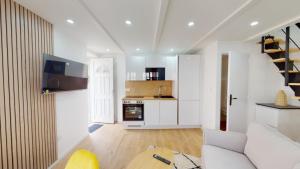 a living room with a white couch and a kitchen at Charmante Maison en Pierre - Centre Ville - Plage in Ouistreham