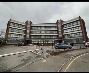 ein großes Gebäude mit Autos auf einem Parkplatz in der Unterkunft 3 Bedroom Flat in Town Centre in Wellingborough