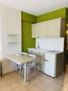 a kitchen with white cabinets and a table and chairs at Harmony Seaside Pelion in Platanias