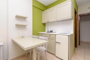 a kitchen with white cabinets and a table and chairs at Harmony Seaside Pelion in Platanias