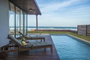 a house with a swimming pool next to the ocean at Illa Blue Village in Trairi