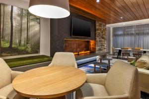 sala de estar con chimenea, mesa y sillas en Fairfield by Marriott Inn & Suites Knoxville Airport Alcoa en Alcoa