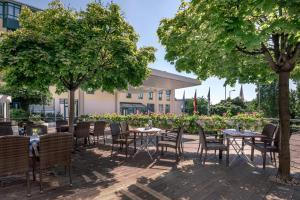 un patio con tavoli, sedie e alberi di Munich Airport Marriott Hotel a Freising