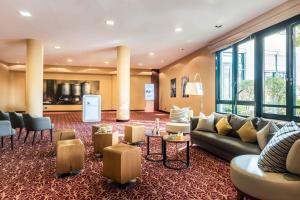 a lobby with a couch and tables and windows at Munich Airport Marriott Hotel in Freising