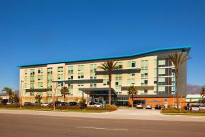 a large building with palm trees in front of a street at Aloft Ontario-Rancho Cucamonga in Rancho Cucamonga