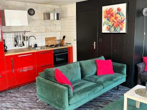 um sofá verde numa cozinha com armários vermelhos em Het Pronkje em Renesse