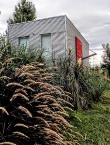 uma casa com uma porta vermelha e alguma relva alta em B&B - El Refugio -C D em Paraná