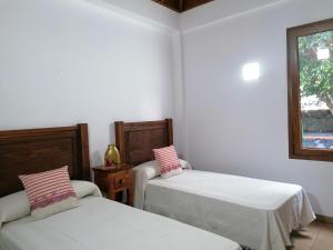 Duas camas num quarto com paredes brancas e uma janela em Casa Amagante, en Hoyo de Mazo em Mazo