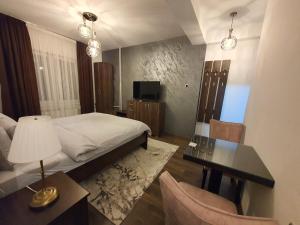 1 dormitorio con cama, mesa y escritorio en IRIS Apartments, en Bitola