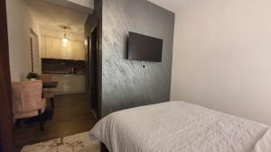 a bedroom with a bed and a television on a wall at IRIS Apartments in Bitola