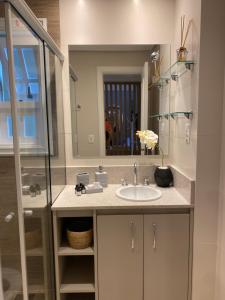 a bathroom with a sink and a mirror at Apartamento proximo a Rua Coberta GIJOCA 01 in Gramado