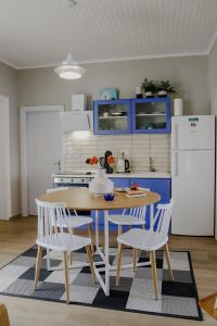 une cuisine avec une table, des chaises et des armoires bleues dans l'établissement Forget Me Not, à Kavala