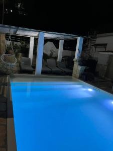 uma grande piscina à noite com luzes azuis em Theodore resort em Áyios Yeóryios