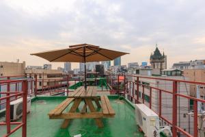 uma mesa de piquenique no telhado de um edifício com um guarda-chuva em The One Hostel Hongdae in Seoul - Foreigner Only em Seul