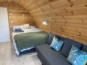 a bedroom with a bed and a couch in a room at Orchard Luxe Glamping Pod in Dungannon