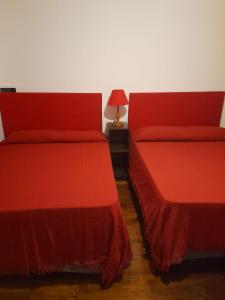 twee rode bedden naast elkaar in een kamer bij Mirador de Estrellas in Tupungato