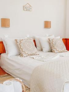 a bed with white sheets and pillows on it at Lindos Athena in Lindos