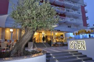 uma árvore sentada em frente a um edifício em Hotel Eden em Bibione