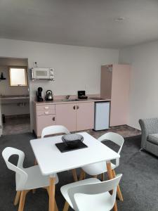 a room with a table and chairs and a kitchen at Apex Motorlodge in Nelson