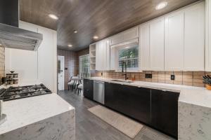 a large kitchen with white cabinets and a stove at Sunset House - Luxury Pool and Hot Tub Retreat in Dallas