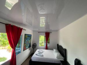 1 dormitorio con 1 cama con cortinas rojas en Hostal Recuerdos del Tayrona, en El Zaino