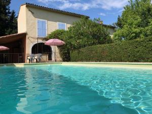 uma casa com uma piscina de água em frente a uma casa em Mas le Pénéquet em Aubignan