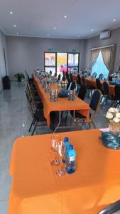 a conference room with orange tables and chairs at LALA POA GUEST HOUSE in Klerksdorp