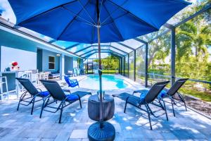 a patio with chairs and an umbrella and a pool at Beautiful Cape Coral Oasis! King Bed, BBQ, Heated Pool, PVT Yard & Much More! in Cape Coral