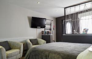 um quarto com uma cama e duas cadeiras e uma televisão em Beautiful studio apartment near the Norfolk Broads em Rackheath