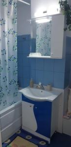 a blue bathroom with a sink and a mirror at Hellen Apartament in Târgovişte