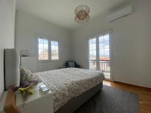 - une chambre blanche avec un lit et des fenêtres dans l'établissement Faliro comfort apartment 10 mins walking to the beach, à Athènes