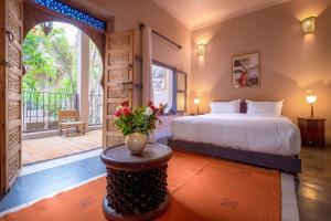 Un dormitorio con una cama y una mesa con un jarrón de flores en Riad Adrar, en Marrakech