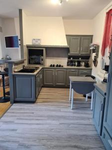 a large kitchen with gray cabinets and a table at Villa Bella à 300 m du Parc Fenestre in La Bourboule