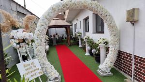 um arco com um tapete vermelho e flores brancas em Casa Lipianu em Târgu Jiu