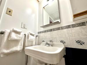 a white bathroom with a sink and a mirror at Capone's Hideaway Motel in Moose Jaw +13 photos