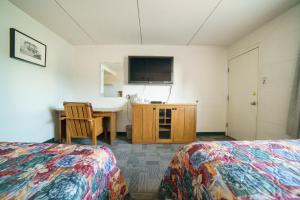 Habitación con 2 camas, lavabo y escritorio. en Capone's Hideaway Motel, en Moose Jaw