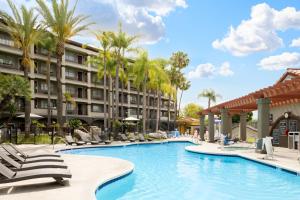 a swimming pool at a resort with chairs and palm trees at Four Points by Sheraton Anaheim in Anaheim